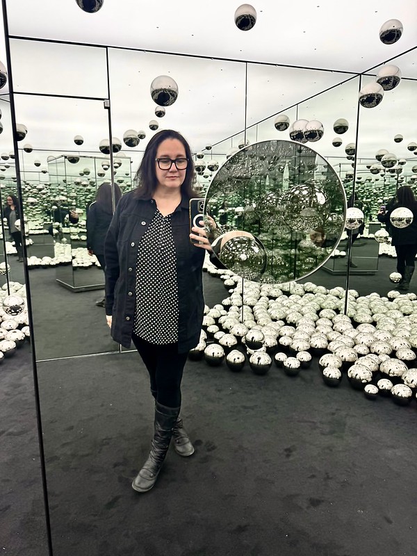 Self-portrait inside Yayoi Kusama's Infinity Mirrored Room, surrounded by reflective spheres and endless reflections