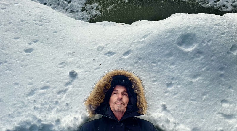 Researcher listening from the snow-covered soil beds beside Bass Lake in winter