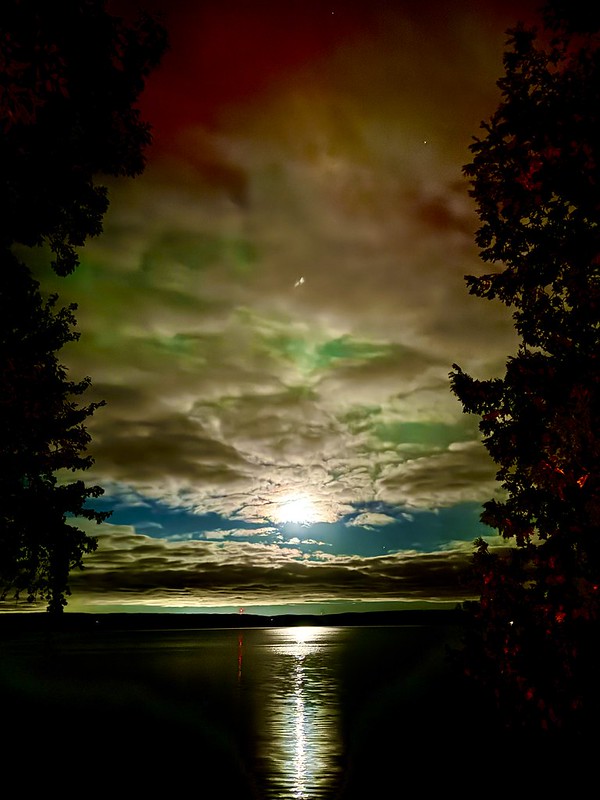 Night sky over Bass Lake after rainfall, moonlight reflected on the water through parted clouds