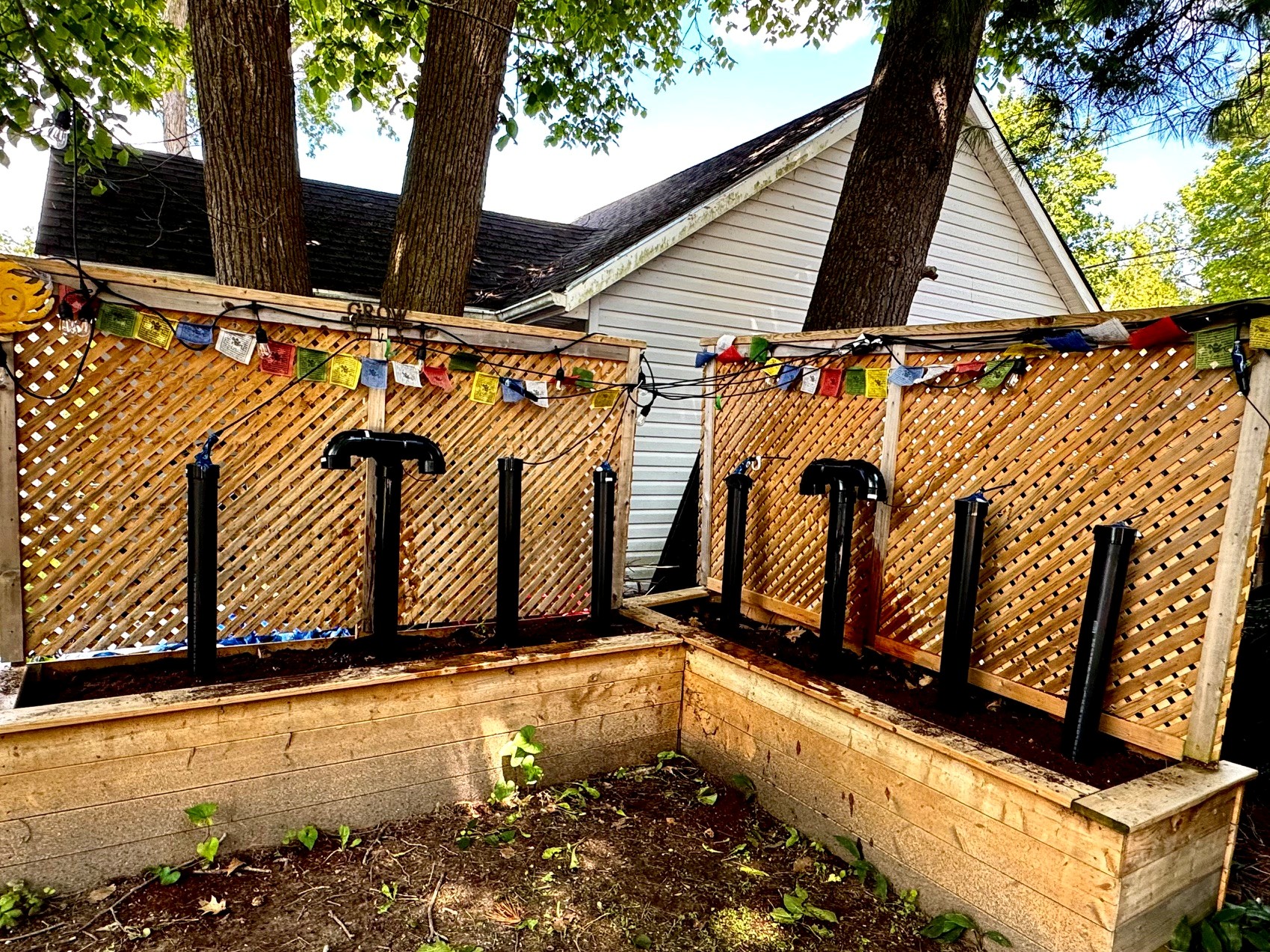 SoilScapes raised beds with eight black monolith sensor tubes, prayer flags strung above